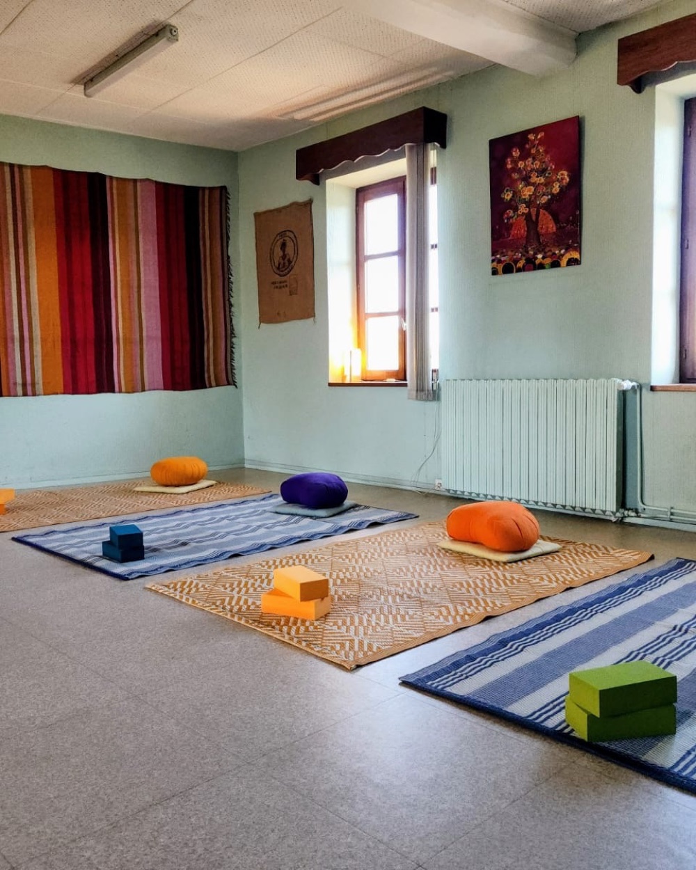 Salle préparée pour une séance de méthode Feldenkrais : tapis, coussins et briques